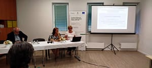 Tájékoztató előadás egy oktatóteremben, az előadóasztalnál ülők és a vetített prezentáció látható.